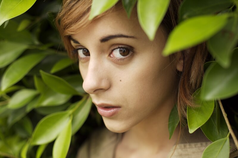 woman peeking through green leaves