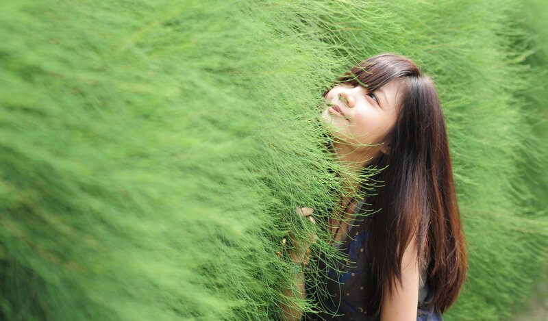 woman peeking through green plants