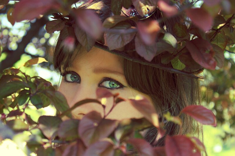 woman peeking through leaves