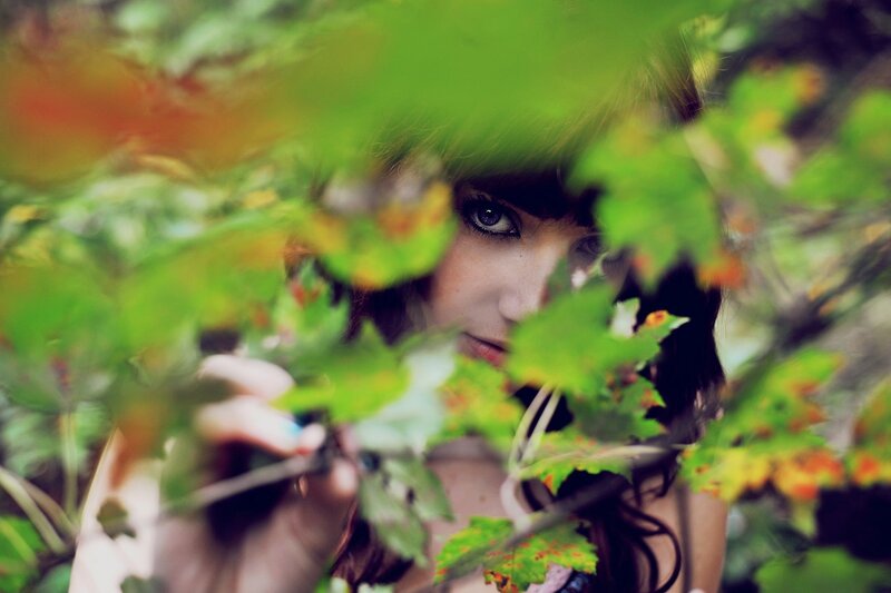 woman peeking through leaves