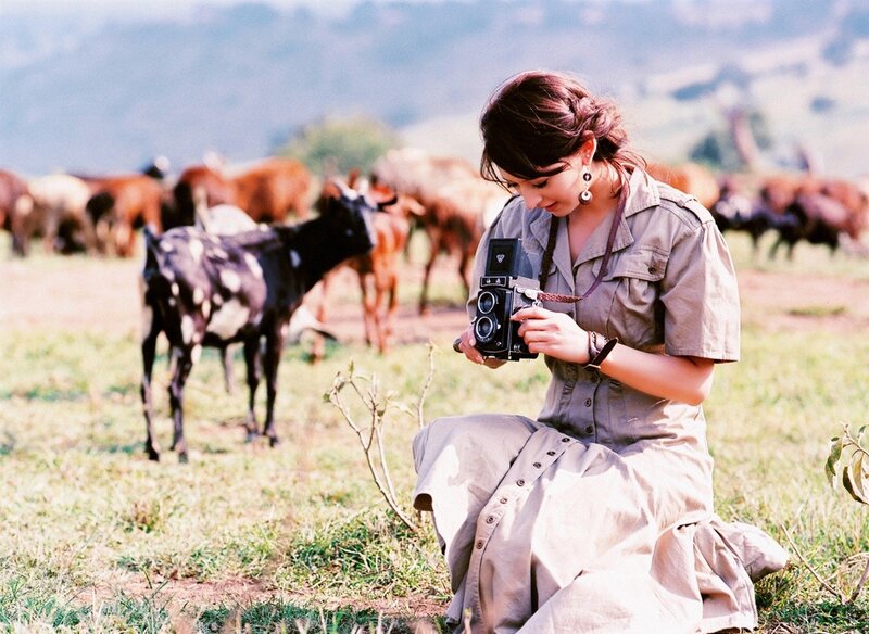 Woman photographing goats in field