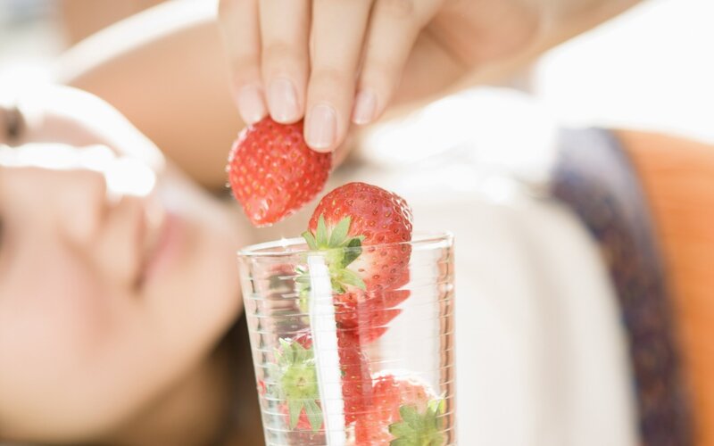 woman placing strawberries in glass