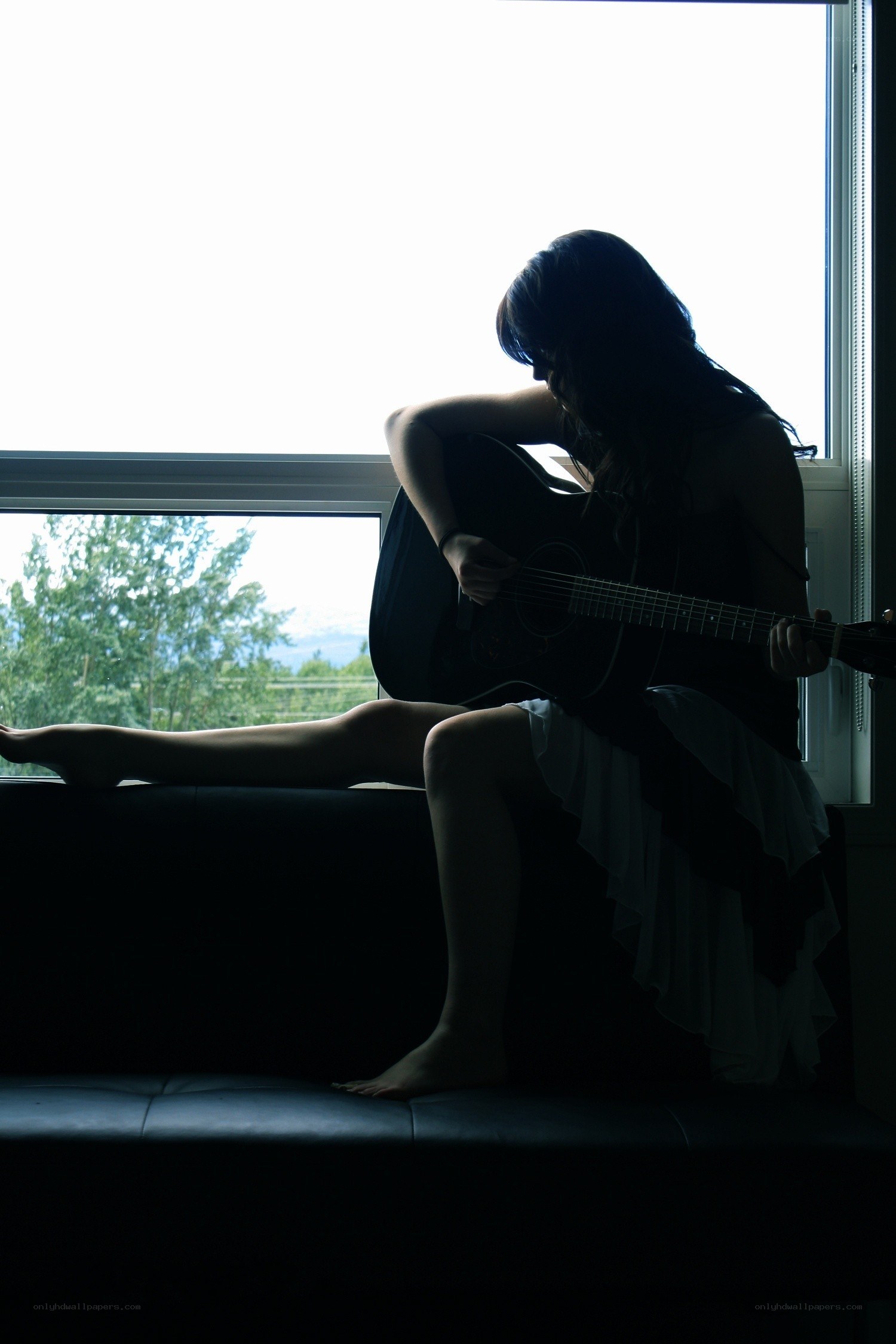 woman playing guitar by window
