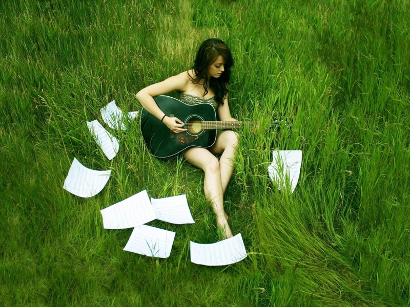 Woman playing guitar in a field