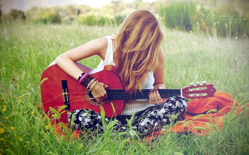 Woman playing guitar in field