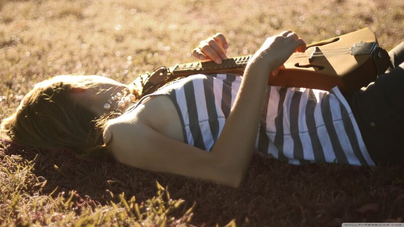 Woman playing guitar on grass