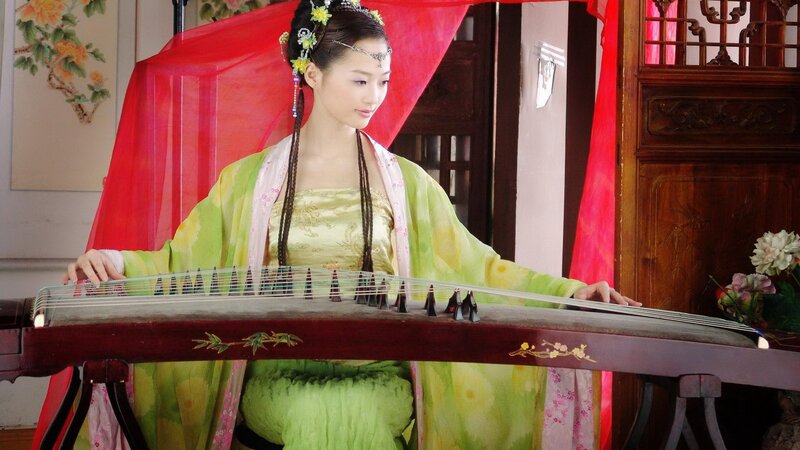 woman playing guzheng in traditional dress