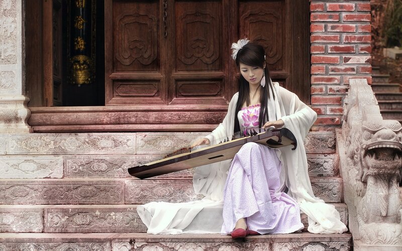 Woman playing guzheng on steps