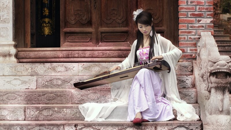 Woman playing guzheng on steps