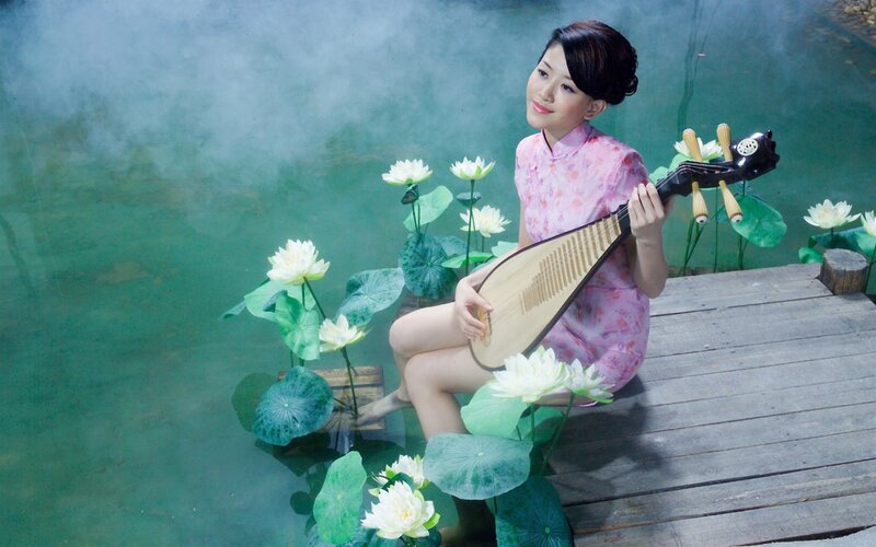 Woman playing pipa by lotus pond