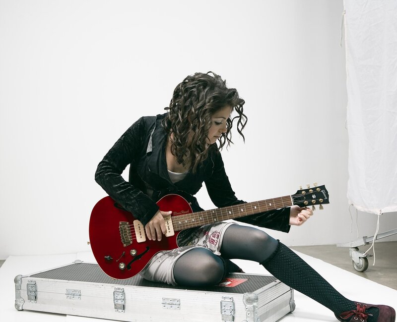 woman playing red electric guitar