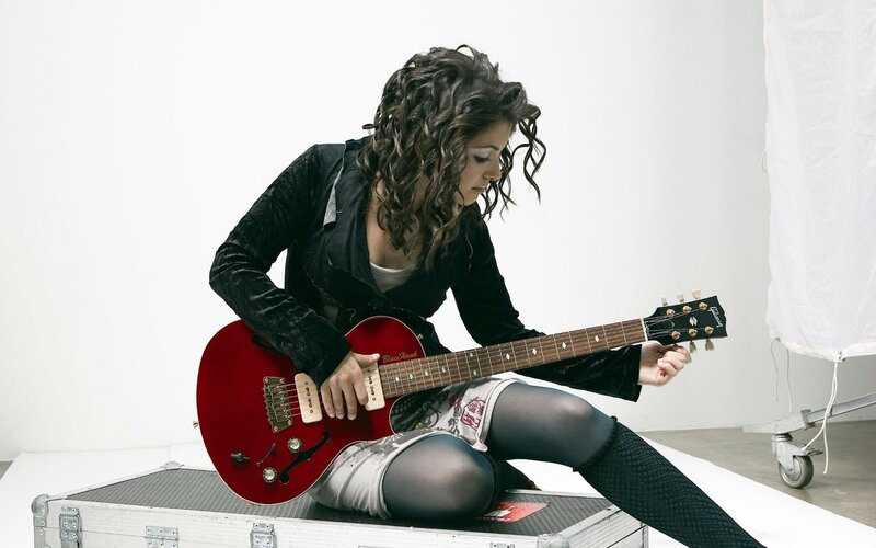 woman playing red electric guitar