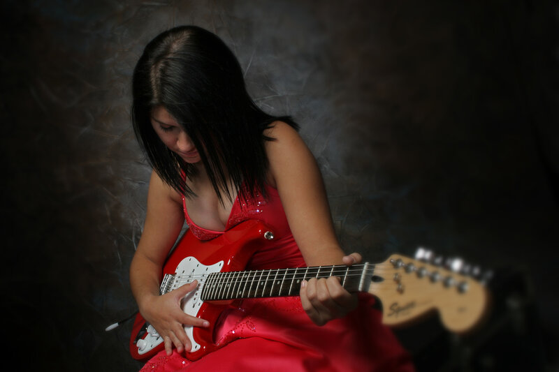 woman playing red electric guitar