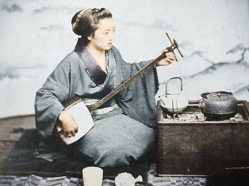 Woman playing shamisen with tea set