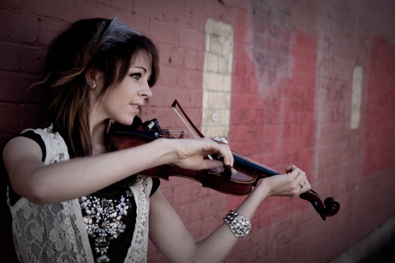 woman playing violin against brick wall
