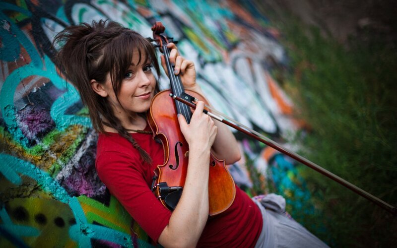 woman playing violin against graffiti