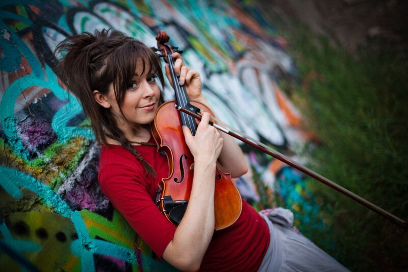 woman playing violin against graffiti