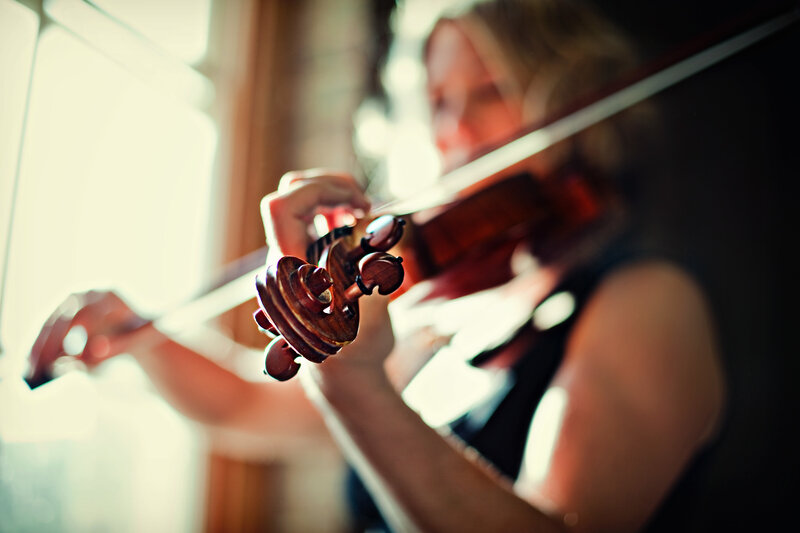 woman playing violin by window