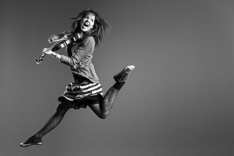 woman playing violin mid-jump