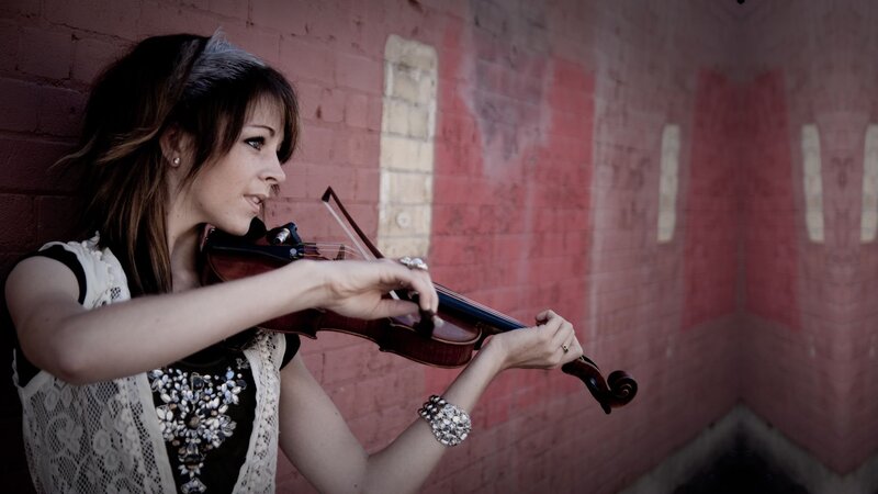 woman playing violin on brick wall