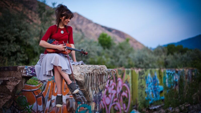 Woman playing violin on graffiti wall