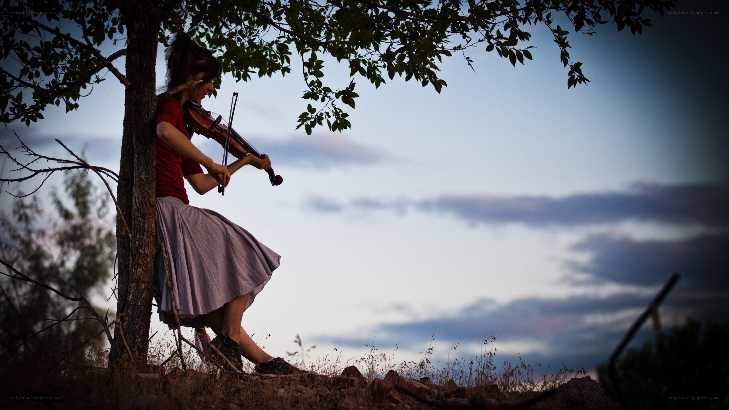 Woman playing violin under a tree