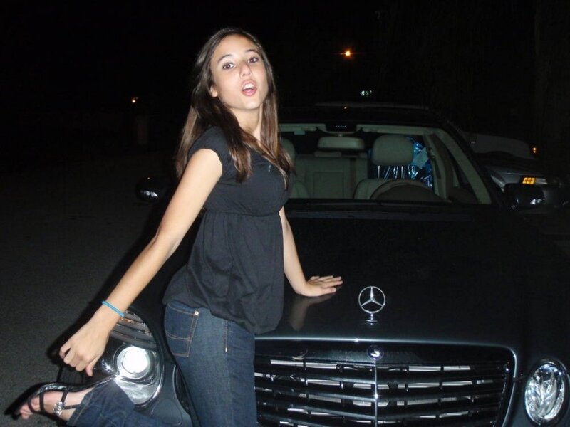 woman posing by car at night