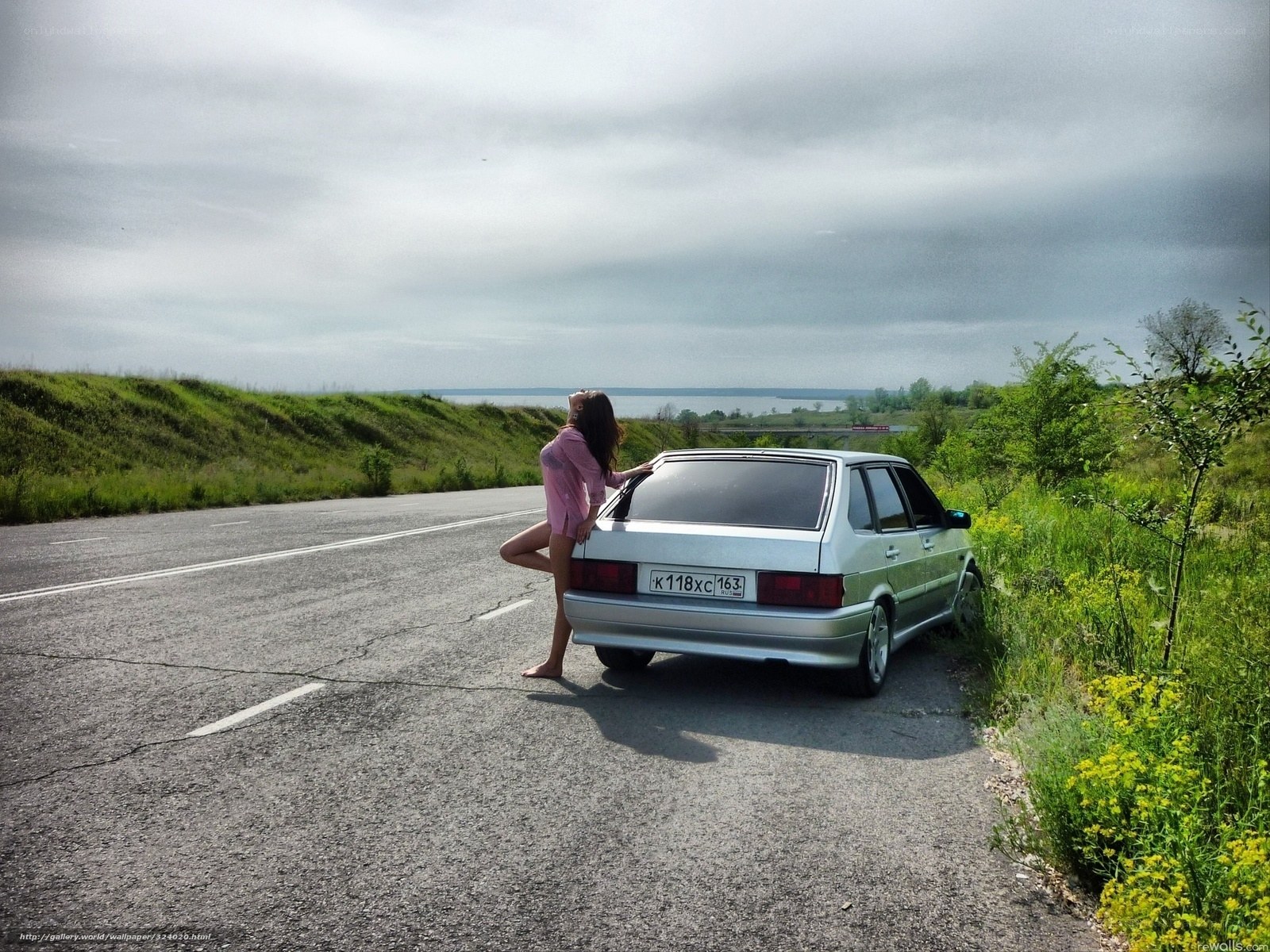 Woman posing by car on road