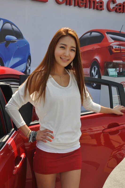 Woman posing by red car