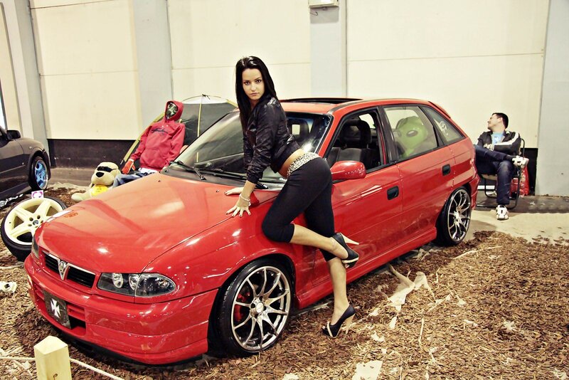 Woman posing by red car