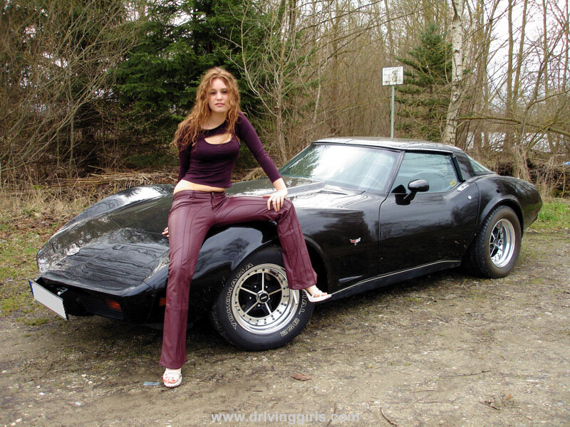 woman posing with a black corvette