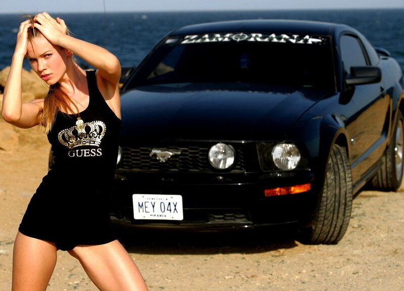 Woman posing with black Mustang