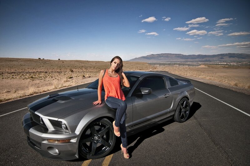 woman posing with muscle car