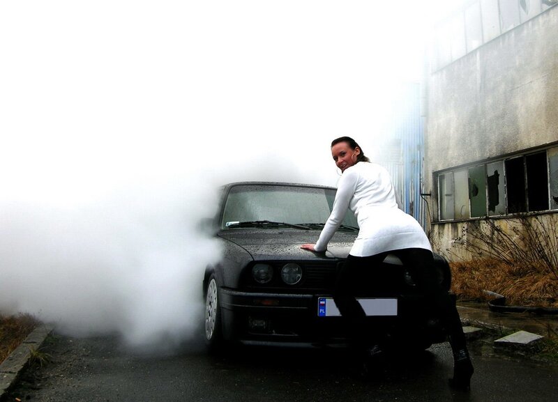 woman posing with smoking car