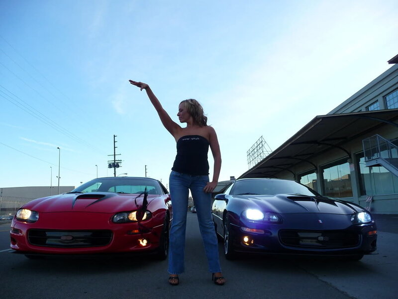 woman posing with two sports cars
