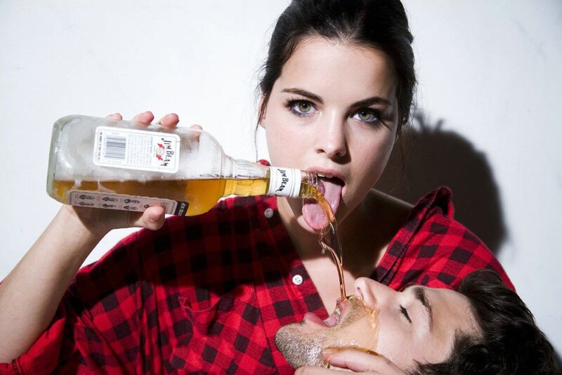 woman pouring liquor into man's mouth