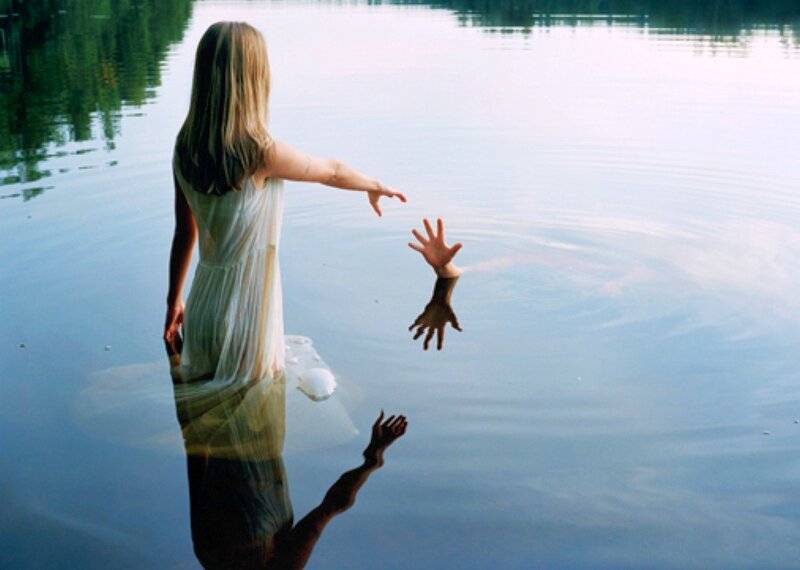 woman reaching for hand in water