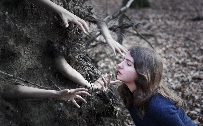 woman reaching for hands from earth