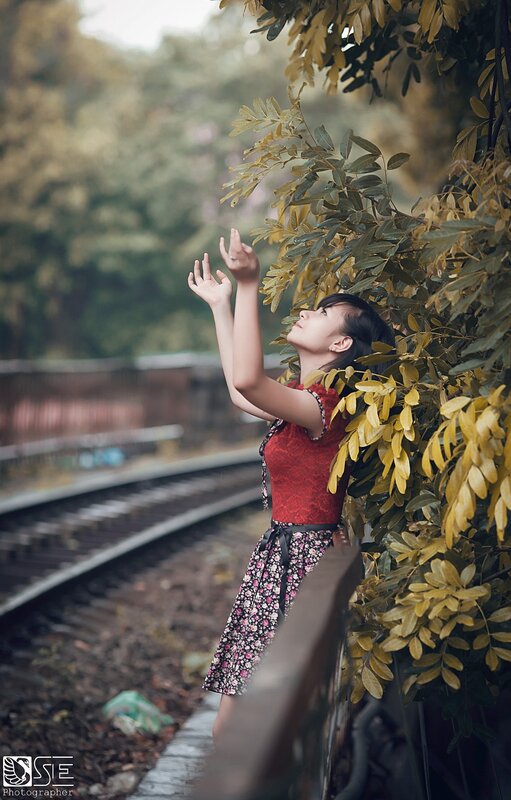 woman reaching for leaves by train tracks