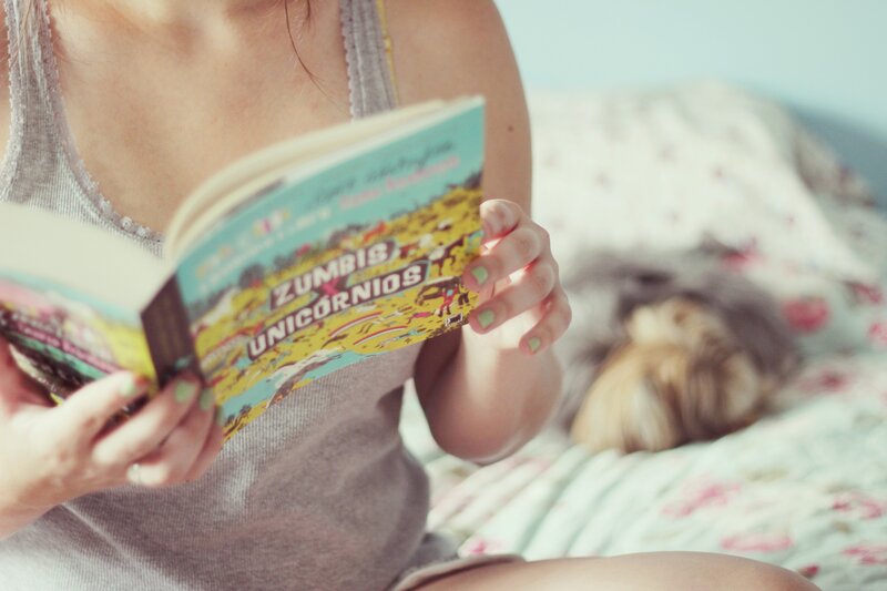 woman reading book on bed