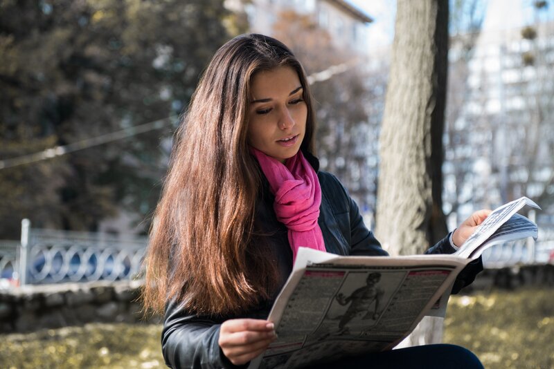 woman reading newspaper outdoors