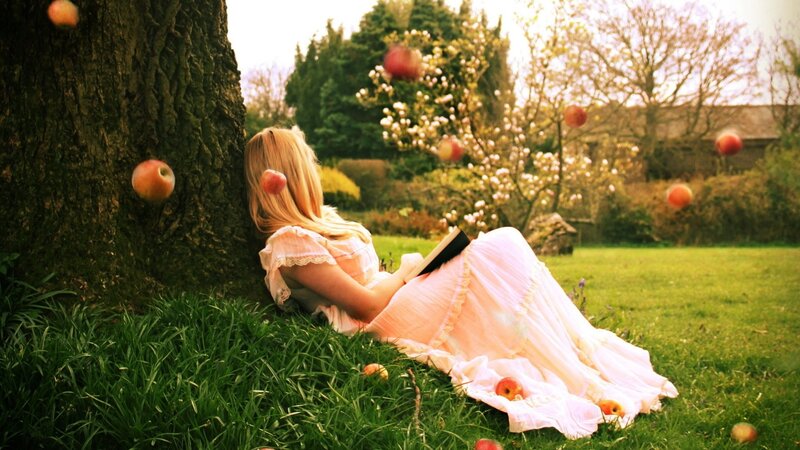 Woman reading under apple tree