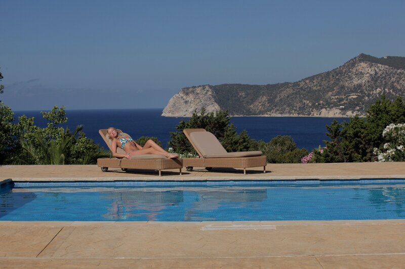 Woman relaxing by pool with sea view