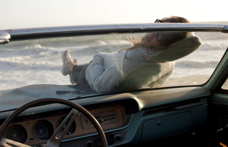 Woman relaxing in car at beach