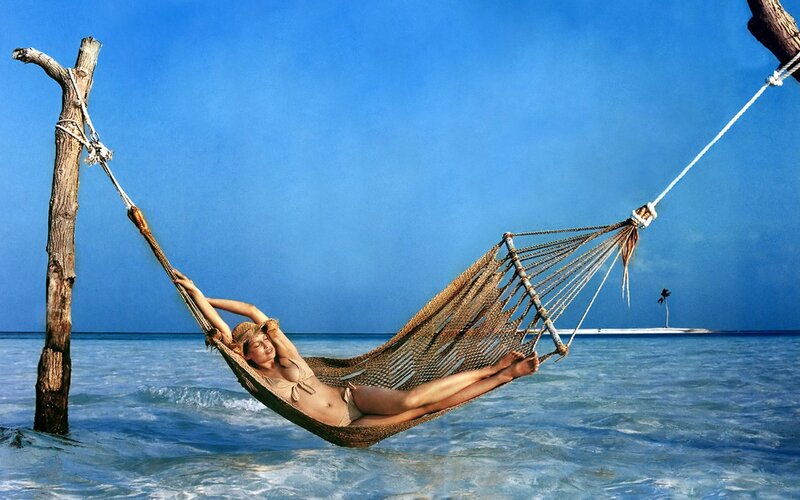 Woman relaxing in hammock on beach