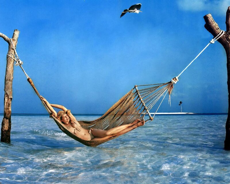 Woman relaxing in hammock on beach