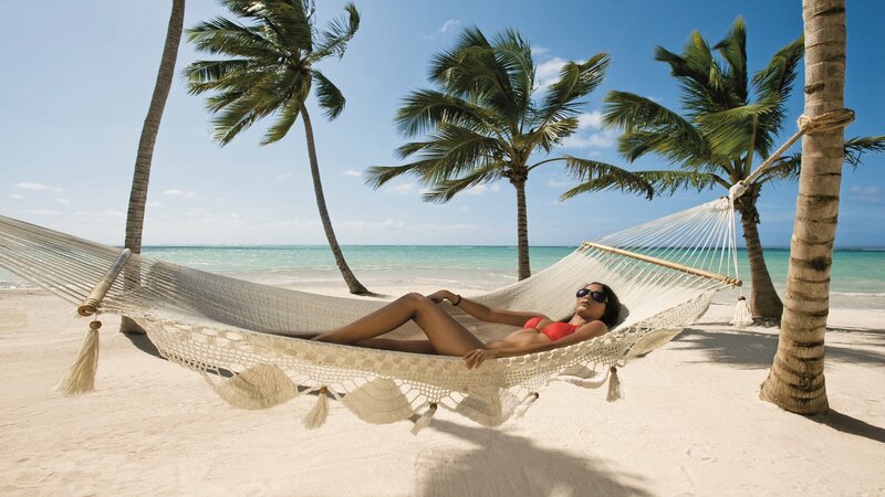 Woman relaxing in hammock on beach