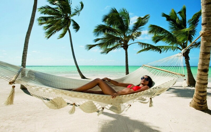 Woman relaxing in hammock on beach