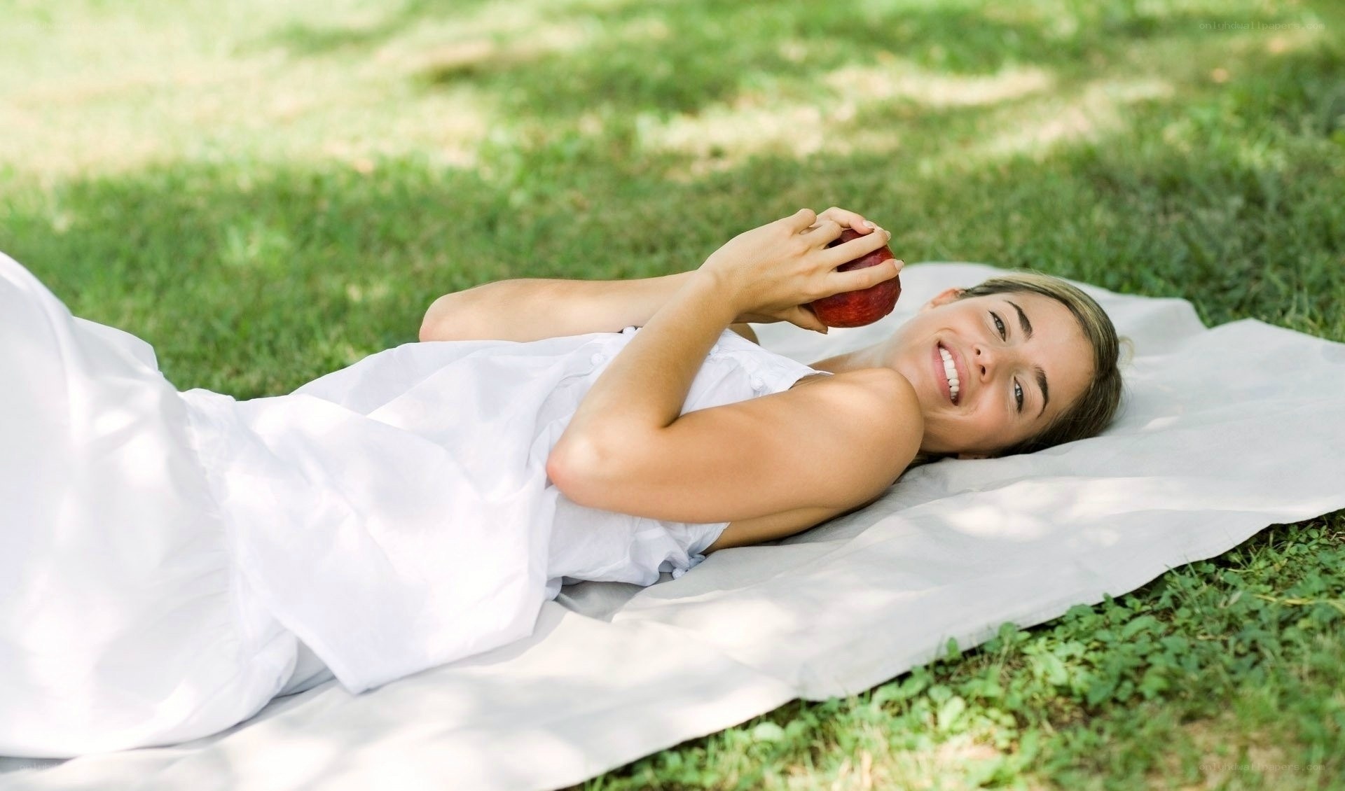 Woman relaxing on grass with apple
