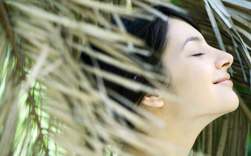 woman relaxing under palm fronds